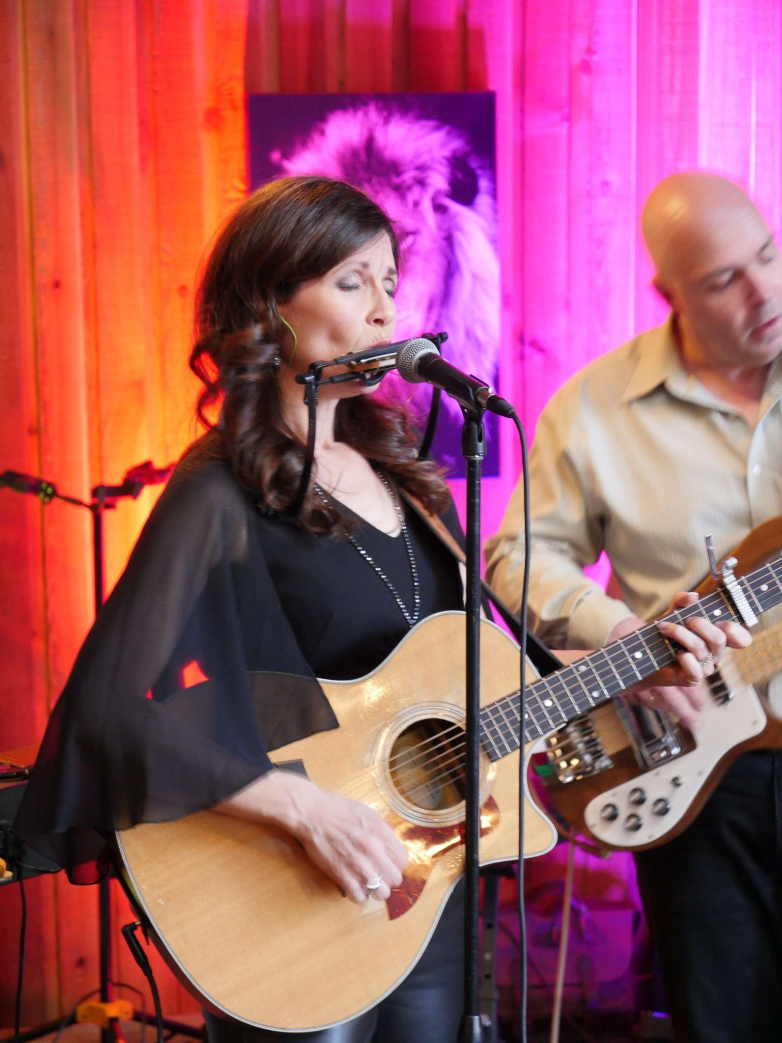 Jacquie Drew playing the guitar and harmonica